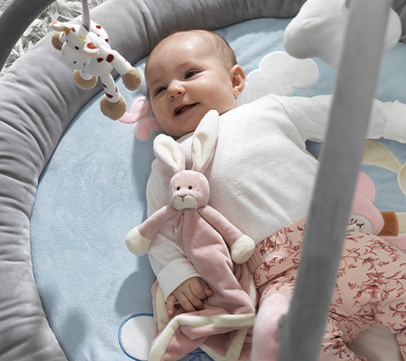Lachendes Baby unter einem Spielbogen